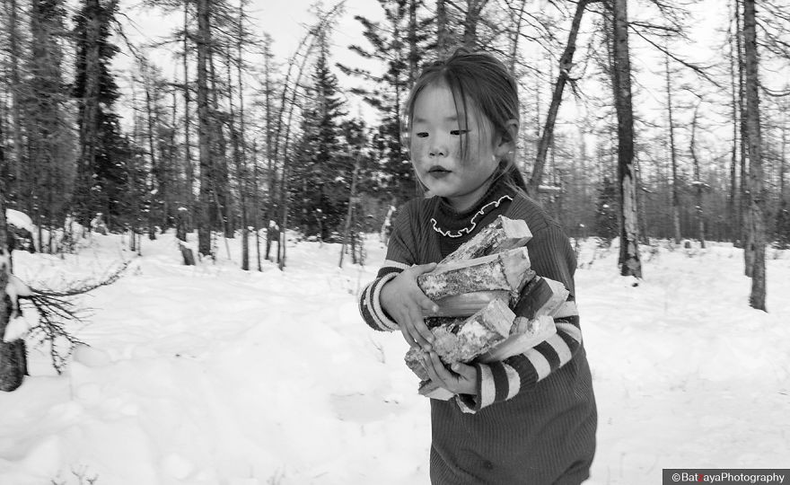 A girl, who glossed her lips, helped the family to collect woods. Winter is time to go to school for children